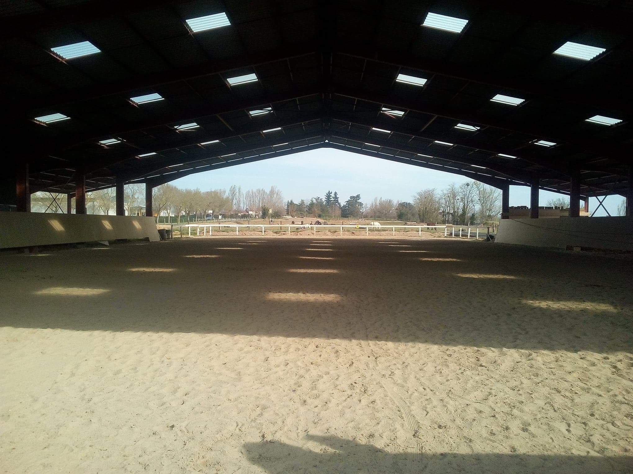 Manège couvert, pour monter à cheval avec une grande carrière dans le prolongement